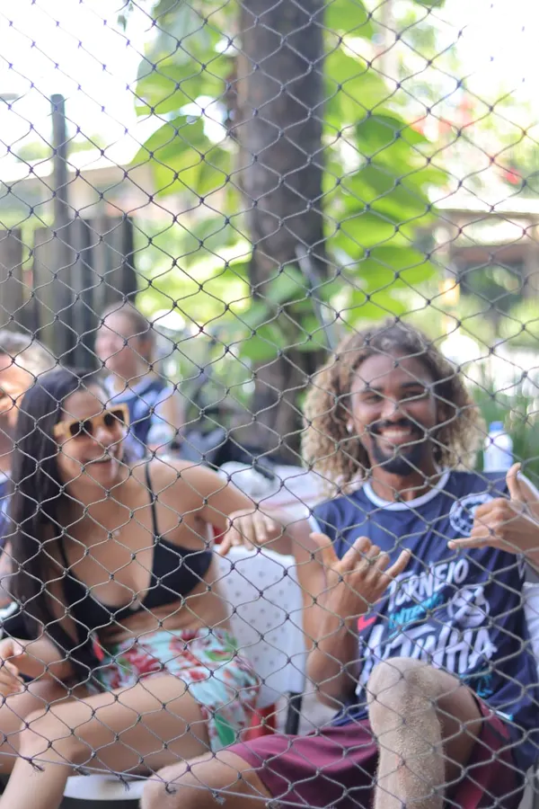Torcida sorrindo vista através da rede da quadra