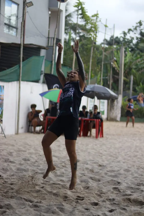 Atleta saltando para alcançar a bola na areia