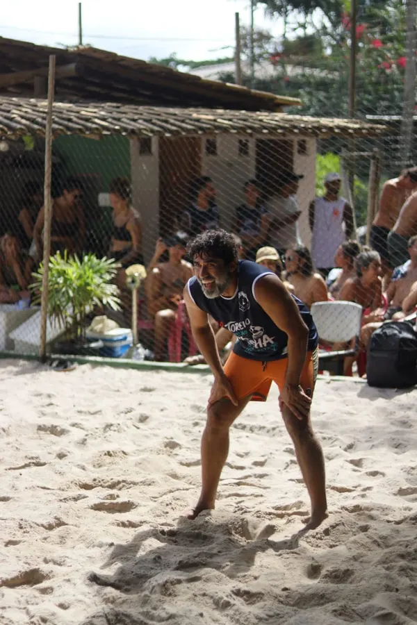 Atleta se esticando para salvar a bola na areia